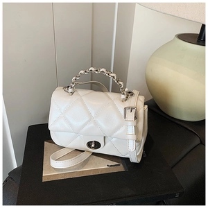 Detail of cream white quilted leather bag with silver twist lock and metal chain handle