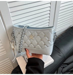 Detail of light blue quilted bucket bag with star metal pieces and starfish charm