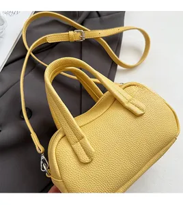 Détail du sac Boston jaune grainé avec doubles poignées et ferrures en métal argenté
