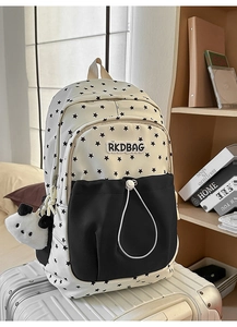 Close-up of student backpack with star print and cute panda plush pendant on white suitcase