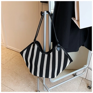 Close-up of black and white striped knit tote bag with leather heart detail