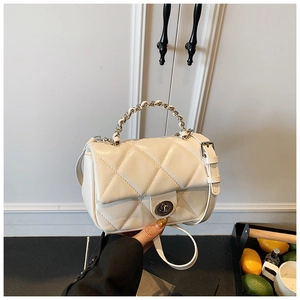 Detail of cream white quilted crossbody bag with metal chain handle and twist lock