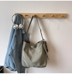 Detail of olive green nylon hobo bag featuring side pocket and casual urban style