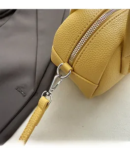 Détail du sac Boston en cuir jaune avec grain de lychee et finitions métalliques argentées