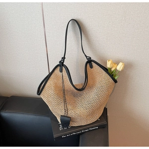 Detail showing the woven straw texture and black leather strap of the large summer tote bag