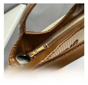 Close-up of golden zipper hardware and woven texture on a brown bucket handbag