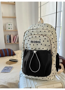 Detail of star-print backpack on a suitcase showing logo patch and front pocket