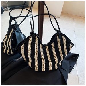 Detailed texture of black and white striped knit mesh shoulder tote bag on a blazer
