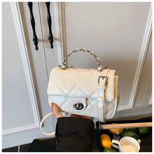 Detail of cream quilted handbag featuring metal chain handle and elegant twist lock closure