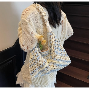 Detail of blue and white crochet tote bag with woven texture and creamy wide shoulder strap