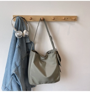 Detail of green nylon tote bag featuring adjustable strap and functional side pocket