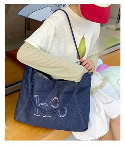 Detailed view of dark blue denim tote bag featuring white artistic HO screen printing