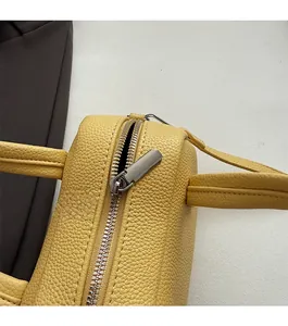 Détail de la fermeture éclair argentée et du cuir jaune grainé du sac Boston chic