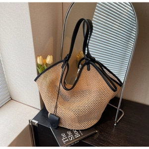 Détail du sac cabas beige en paille tressée avec poignées et finitions en cuir noir