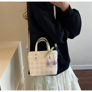 Detail of checkered crossbody bucket bag with tulip charm and elegant leather strap