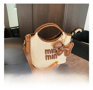 Detail of woven straw handbag with brown leather trim and cute puppy charm accessory