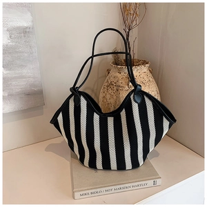 Detail of woven black and white striped tote bag with knotted black leather handles
