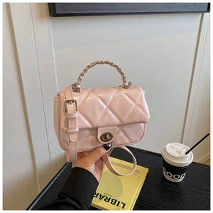 Detail of cherry pink quilted handbag featuring metallic twist lock and woven handle