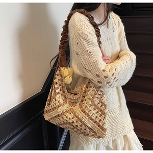 Detail view of woven straw beach bag featuring intricate hollow knit and leather shoulder strap
