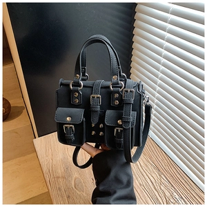 Close-up of black retro motorcycle style handbag with silver buckles and rivets