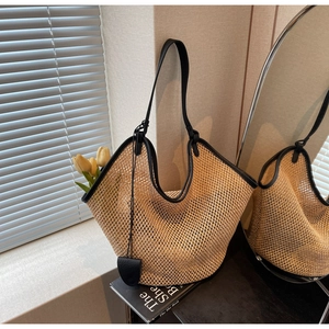 Détail d'un grand sac cabas en paille beige avec finitions et bandoulière en cuir noir