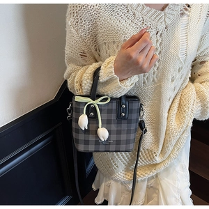 Detail of checkered bucket bag featuring tulip charm and stylish bow decoration