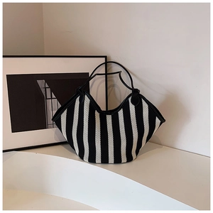 Detail of large woven tote bag with black and white vertical stripes and leather handles