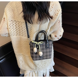 Detail of grey plaid mini bucket bag with white tulip charms on a model's outfit