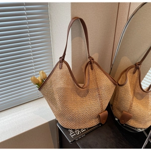 Détail du tissage et de la bandoulière en cuir marron d'un grand sac cabas d'été en paille