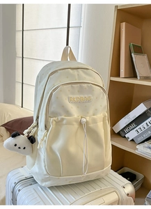 Detail view of cream canvas backpack with star pattern and cute panda plush pendant charm