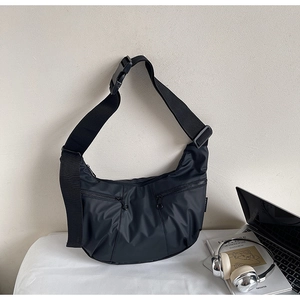 Detail of black nylon crescent crossbody bag with utility zipper pockets and adjustable strap