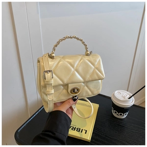 Detail shot of pale yellow quilted crossbody bag with golden chain handle and swivel lock
