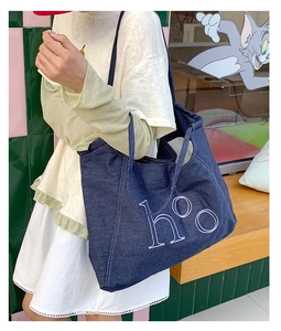 Detail of dark blue denim tote bag with white ho embroidery and contrast stitching