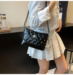 Close-up of black quilted patent leather bag with star charm and silver chain strap