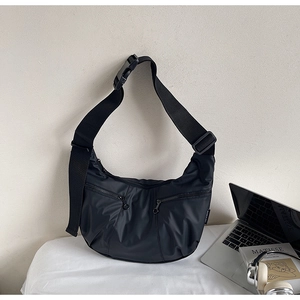Detail shot of black crescent shoulder bag with metallic zippers and nylon strap