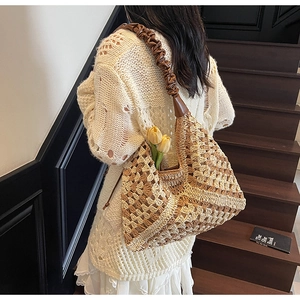 Detail of handcrafted crochet shoulder bag featuring pleated brown straps and floral accents