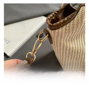 Detail of premium golden metal hook and brown leather trim on the woven straw basket bag