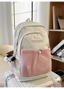Detail of canvas backpack with pink star print and cute panda plush charm on a suitcase