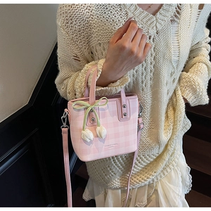 Pink checkered bucket bag featuring tulip pendants and a green bow accessory detail