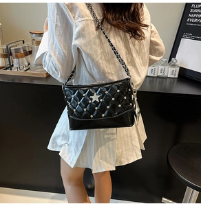 Detail of black quilted chain bag with star studs worn as a chic crossbody