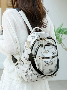Sac à dos blanc avec imprimés papillon noirs et fermetures éclair pour le voyage