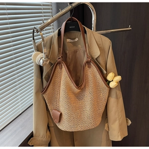 Détail d'un sac cabas en paille tissée avec bordure en cuir contrastée et breloque chic