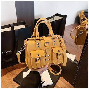Detail of bright yellow multi-pocket boston bag featuring silver studs and buckle straps