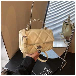 Detailed close-up of quilted cream crossbody bag with silver chain handle and swivel lock