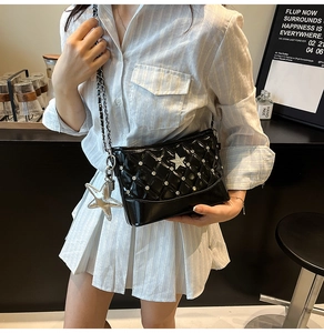 Detail of black patent leather bucket bag with diamond quilting and silver star charms