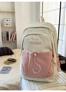 Detail of pink and white star pattern backpack on suitcase in cozy home setting