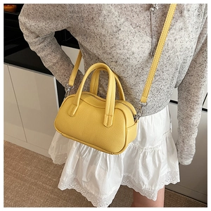 Sac boston jaune grainé porté par un mannequin dans un décor de vie quotidienne intérieur