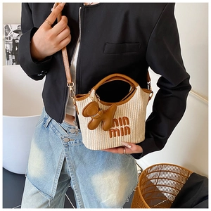 Close-up of woven straw handbag featuring leather trim and a cute dog charm accessory