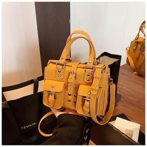 Close-up of bright yellow leather handbag with silver rivets and dual pocket detail