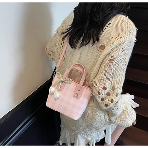 Detail of pink plaid bucket bag featuring tulip charm and fashion text decoration